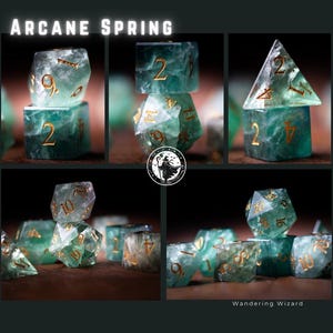 Puede incluir: Un conjunto de dados de m&uacute;ltiples caras en varias formas y tama&ntilde;os. Los dados son de color verde azulado transl&uacute;cido con n&uacute;meros dorados. El texto "Arcane Spring" est&aacute; en la parte superior de la imagen y "Wandering Wizard" en la parte inferior.