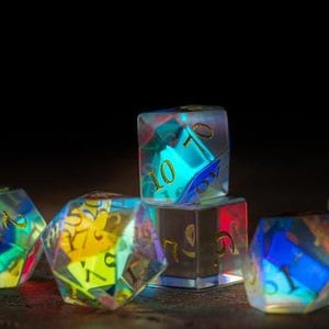 May include: A collection of iridescent, multi-sided dice with gold numbering. The dice are clear with internal color gradients of blue, green, and yellow. The dice are lit from within, creating a glowing effect against a dark background.