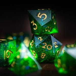 May include: A selection of green and gold polyhedral dice, perfect for tabletop gaming. The dice are emerald green with gold numbering. The image is well-lit, highlighting the details of the dice. The dice are scattered, suggesting a recent roll.