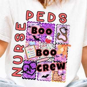 May include: White t-shirt with a colorful graphic design. The design features the words "NURSE PEDS BOO CREW" in pink and black, along with Halloween-themed medical icons like a stethoscope, syringe, and bandage.