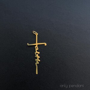 K&ouml;nnte beinhalten: Ein goldfarbener Anh&auml;nger in Form eines Kreuzes mit dem Wort "faith" vertikal geschrieben. Der Anh&auml;nger ist an einer kleinen Schlaufe aufgeh&auml;ngt. Der Hintergrund ist eine dunkle, strukturierte Oberfl&auml;che.