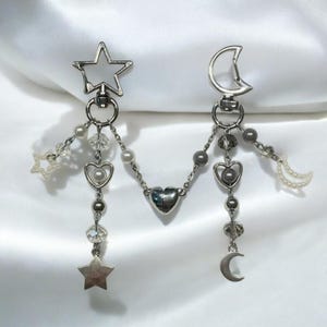 Pu&ograve; includere: Un braccialetto con ciondoli in argento a forma di stella, luna e cuore. I ciondoli sono attaccati a una catena d'argento con piccole perline. Il braccialetto &egrave; perfetto per aggiungere un tocco di fantasia a qualsiasi outfit.