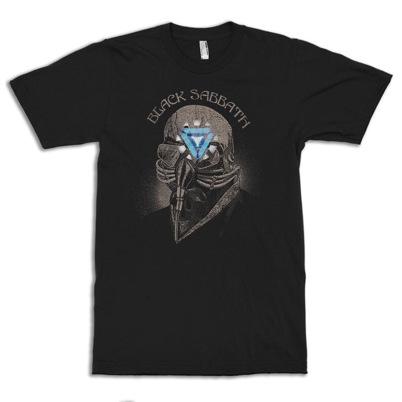 May include: Black t-shirt featuring the band name "Black Sabbath" above a detailed illustration. The illustration depicts a skeletal figure with a blue triangle in place of an eye. The design is in shades of gray and blue.