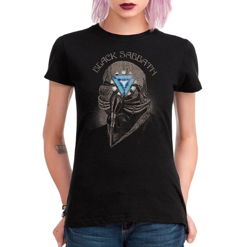 May include: Black t-shirt featuring a graphic of a skull wearing a respirator with a blue and white triangle design. The text "BLACK SABBATH" is arched above the skull. The shirt is a classic crew neck style.