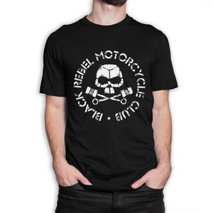 May include: Black t-shirt with a white graphic. The graphic includes a skull, crossed pistons, and the text "BLACK REBEL MOTORCYCLE CLUB" in a distressed font. The design is centered on the chest.