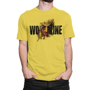 Peut inclure: Un t-shirt jaune vif à manches courtes avec une impression graphique du personnage Wolverine. Le motif présente le texte noir en gras "WOLVERINE" superposé sur une illustration artistique et vieillie du visage et du masque du personnage.