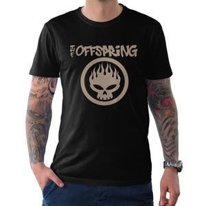 Pode incluir: Camiseta preta com o nome da banda "The Offspring" em uma fonte estilizada acima de um logotipo circular. O logotipo é uma caveira com chamas, tudo em bege. A camiseta é de manga curta.