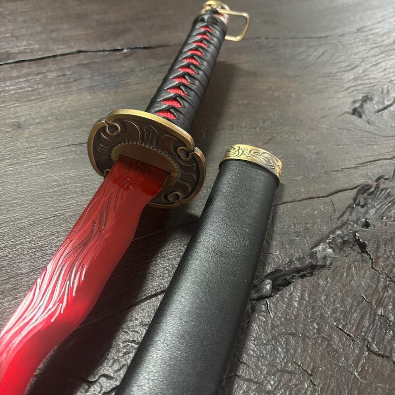 May include: A decorative sword with a red blade and black handle. The handle is wrapped with red stitching. The sword has a gold-colored guard and a black scabbard with gold accents. The blade has etched designs.