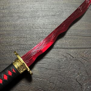 May include: A red and gold decorative dagger with a black handle. The blade has a wave-like pattern. The handle is black with red diamond-shaped accents and gold filigree.