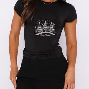 May include: Black t-shirt with a white design of three Christmas trees and the text "Merry Christmas".