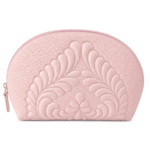 Peut inclure: Une trousse de toilette rose clair en forme de demi-cercle avec une surface texturée et grainée. L'avant présente un motif matelassé symétrique et proéminent composé de formes incurvées en plumes. Une fermeture éclair rose assortie.