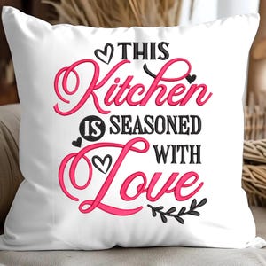 May include: White pillow with pink and black embroidery that reads "This Kitchen is Seasoned with Love".