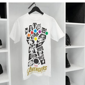 May include: White t-shirt with a black and white graphic of the Infinity Gauntlet from Avengers: Infinity War. The gauntlet is made up of various Marvel character symbols and the Infinity Stones are depicted in their respective colors. The text "Avengers Infinity War" is printed in gold below the graphic.