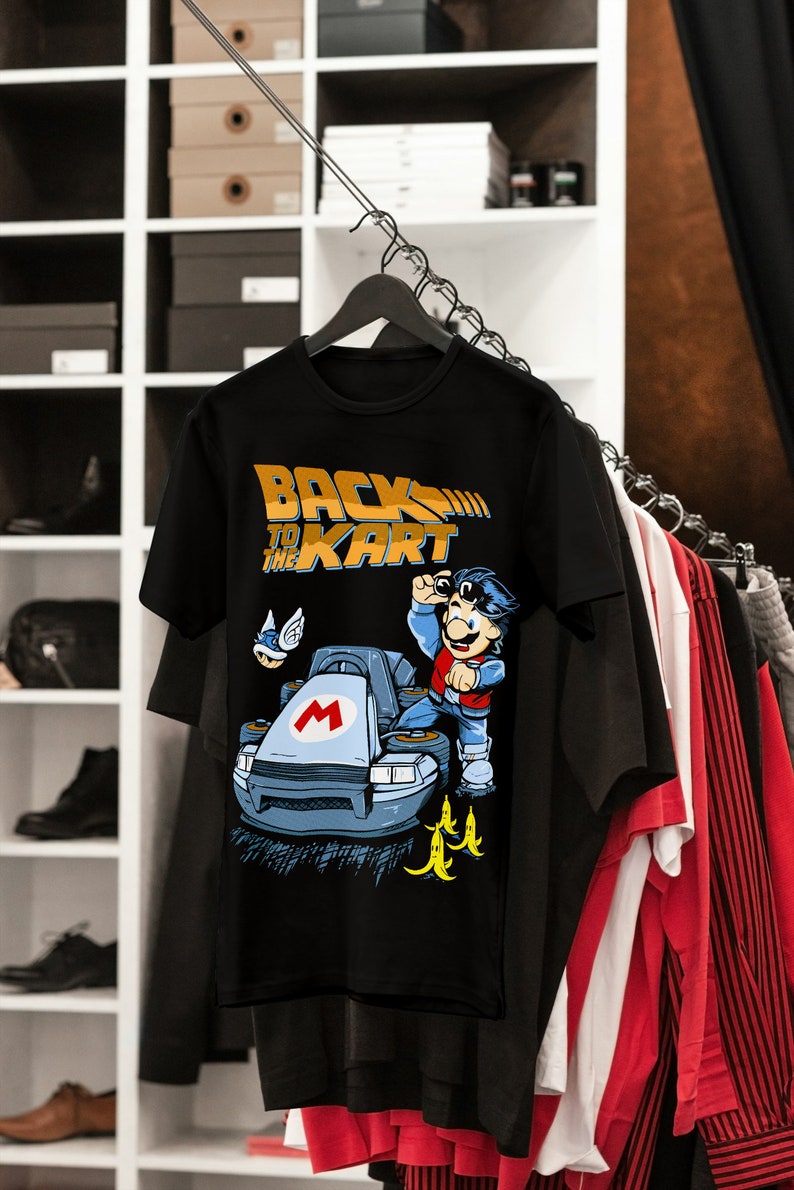 May include: Black t-shirt with a graphic of a cartoon character driving a go-kart. The text "Back to the Kart" is printed in yellow on the shirt.