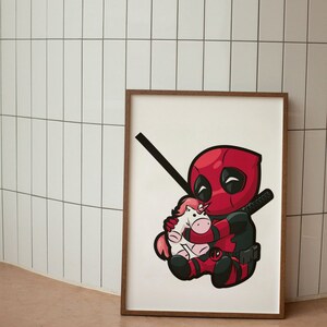 Pu&ograve; includere: Una stampa incorniciata di un'illustrazione di cartone animato di Deadpool che tiene un peluche di unicorno rosa. Deadpool indossa il suo costume rosso e nero caratteristico e ha un'espressione maliziosa sul viso.