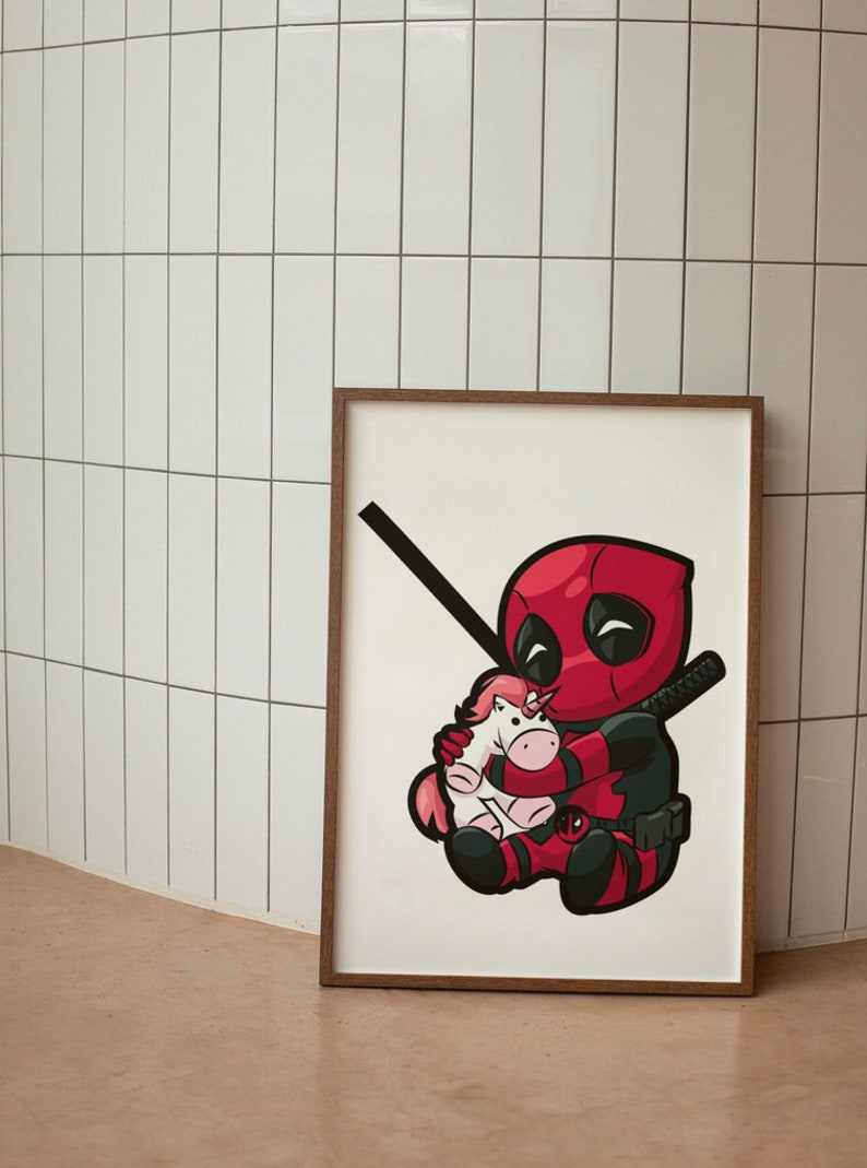 Pu&ograve; includere: Una stampa incorniciata di un'illustrazione di cartone animato di Deadpool che tiene un peluche di unicorno rosa. Deadpool indossa il suo costume rosso e nero caratteristico e ha un'espressione maliziosa sul viso.