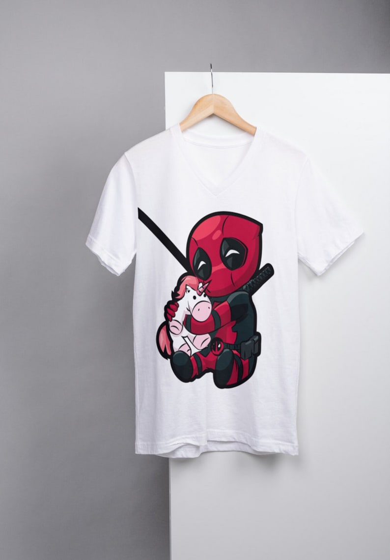 Pu&ograve; includere: Maglietta bianca a collo a V con una stampa grafica di un personaggio Deadpool rosso e nero che tiene un unicorno rosa.