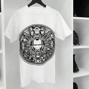 May include: White t-shirt with a black and white graphic print of a circle with the word "MARVEL" and various Marvel characters, including Iron Man, Captain America, Spider-Man, and Black Panther.