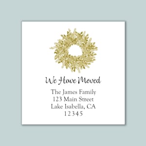 May include: A square white card featuring a gold watercolor wreath illustration at the top. The text reads: We Have Moved, The James Family, 123 Main Street, Lake Isabella, CA 12345. The design uses a combination of script and serif fonts.