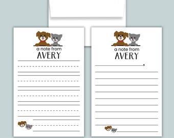 May include: Two white stationery sheets with a brown dog and gray cat illustration at the top, the text A NOTE FROM AVERY, and lined writing space. One sheet has dashed lines, the other solid lines. A red pencil lies horizontally below the sheets.