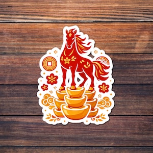 Puede incluir: Una pegatina con un caballo rojo con detalles amarillos, de pie sobre lingotes de oro. El diseño incluye motivos florales y de monedas, enmarcado por un borde blanco, sobre un fondo de madera. Una pegatina decorativa.