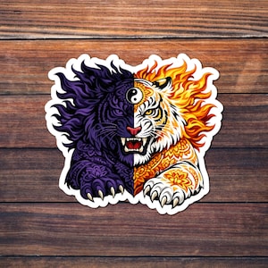 Puede incluir: Una pegatina con un diseño dividido de un tigre y un león. El lado izquierdo es morado con patrones intrincados, mientras que el lado derecho es naranja y amarillo. Un símbolo de yin-yang está en el centro, sobre la nariz del tigre.