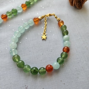 May include: A bracelet made of green, blue, and orange beads with a gold star charm.