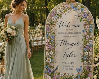 May include: An arched wedding welcome sign on a wooden easel, featuring a floral border with daisies, blue and purple flowers, a small bird, and a butterfly. The text reads: Welcome to our wedding celebration, Margot and Tyler, Boston, USA, 07.15.2026.