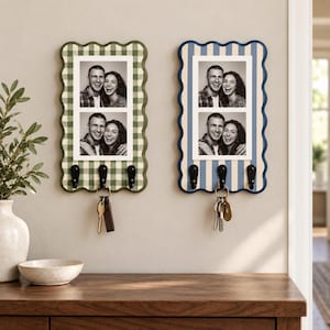 May include: Two rectangular wall-mounted organizers with scalloped edges, each featuring a photo frame displaying two black and white portraits and three black metal hooks. One organizer has a green gingham pattern, the other has blue stripes.