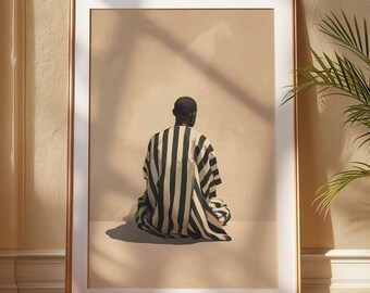 May include: A framed art print showing a person in a black and white striped garment, seated with their back to the viewer. The artwork is set against a neutral background, framed in gold, and displayed in a room with natural light.