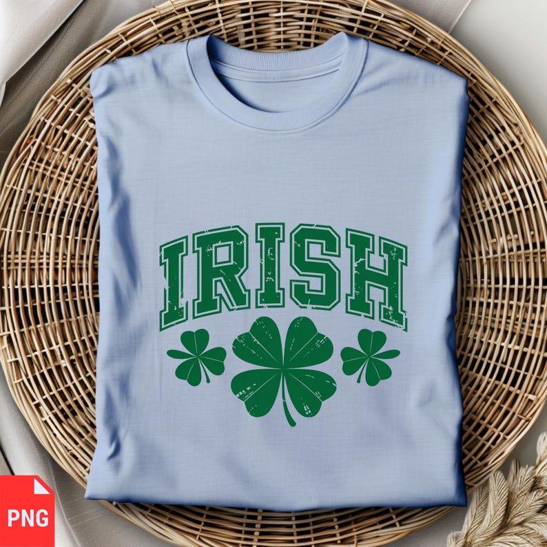 Puede incluir: Camiseta azul claro con la palabra "IRISH" en una fuente universitaria vintage verde. Tres tr&eacute;boles verdes est&aacute;n debajo de la palabra.