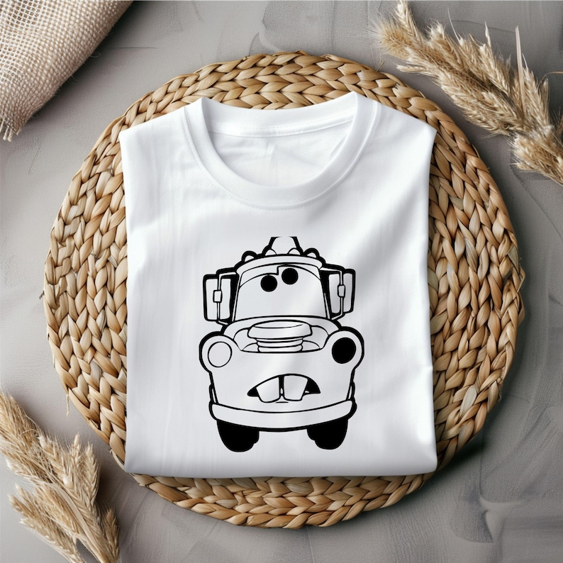 Puede incluir: Una camiseta blanca con una ilustraci&oacute;n en blanco y negro de Mater de la pel&iacute;cula Cars de Disney Pixar. Mater es una gr&uacute;a con una gran sonrisa y ojos grandes.