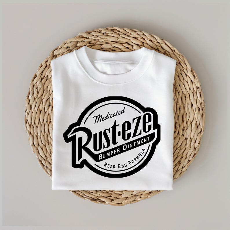 Puede incluir: Camiseta blanca con un gr&aacute;fico en blanco y negro de un c&iacute;rculo con el texto "Medicated Rust-eze Bumper Ointment Rear End Formula" en su interior.