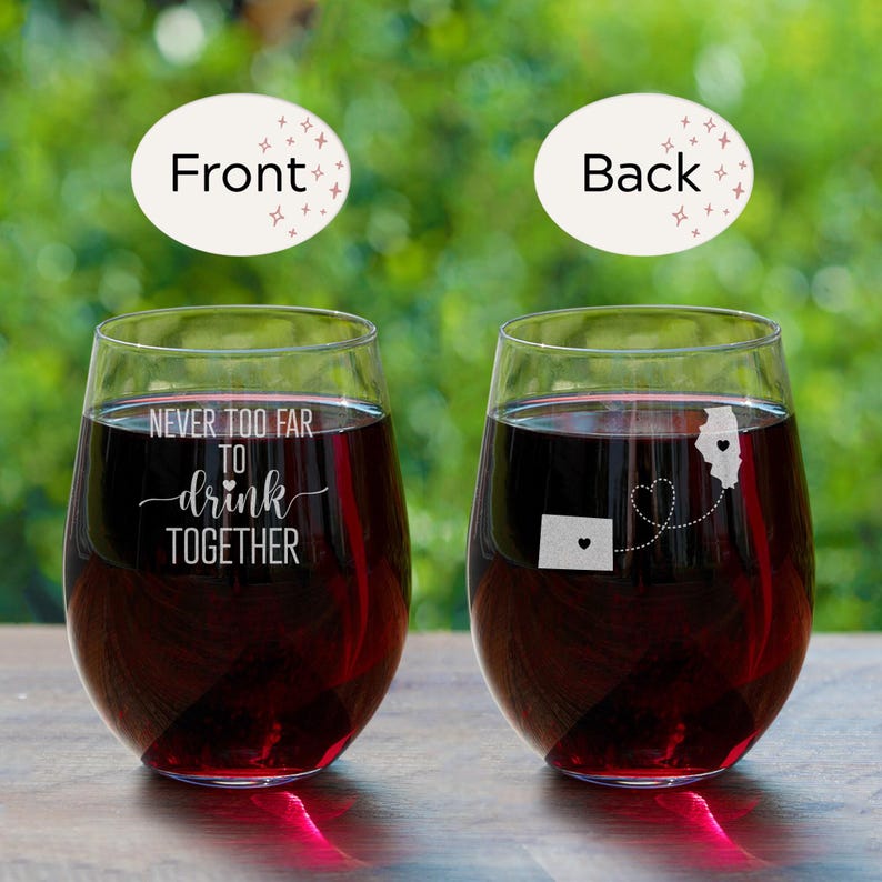 Puede incluir: Dos copas de vino transparentes con vino tinto. Una copa tiene el texto "Never too far to drink together" grabado en la parte delantera. La otra copa tiene un coraz&oacute;n y dos estados, Illinois y Colorado, grabados en la parte posterior.