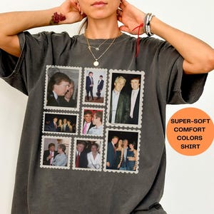 Op de afbeelding: Donkergrijs T-shirt met een postzegelontwerp met vintage foto's. Het shirt heeft een relaxte pasvorm en de tekst "SUPER-SOFT COMFORT COLORS SHIRT" in een oranje cirkel.