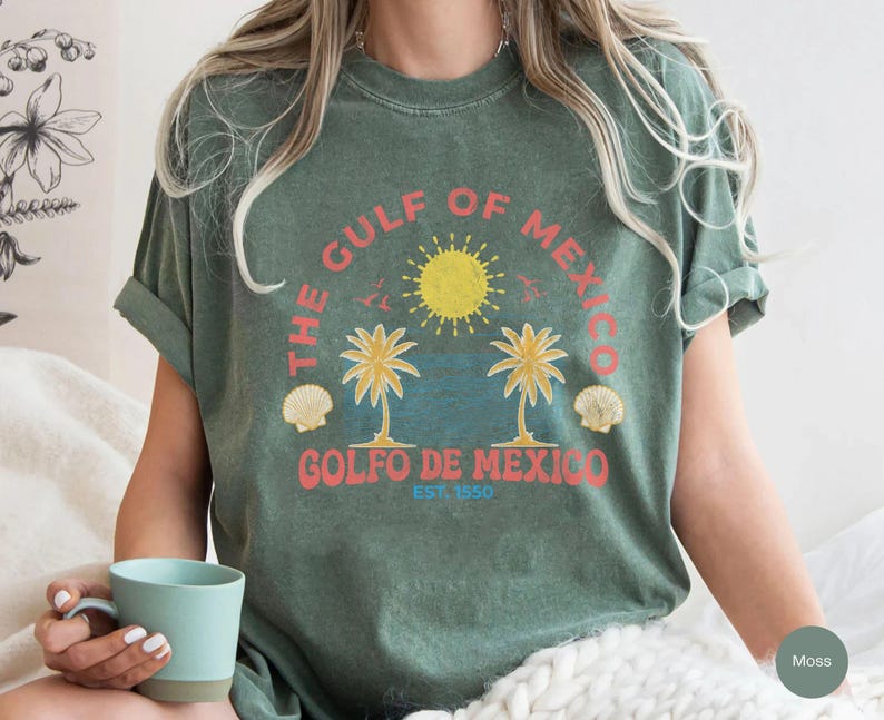 K&ouml;nnte beinhalten: Ein gr&uuml;nes T-Shirt mit einem Vintage-Grafikdruck von Palmen, einer Sonne und Muscheln. Der Text auf dem Shirt lautet "The Gulf of Mexico, Golfo de Mexico, Est. 1950".