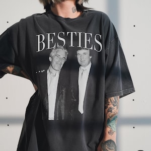 May include: Graphite-coloured t-shirt featuring the word "BESTIES" in white above a black and white image of two men. The shirt has a relaxed fit.