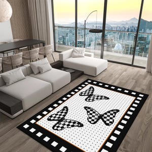 May include: Black and white chequered butterfly rug with a white background and black polka dots. The rug has a black border with white squares.