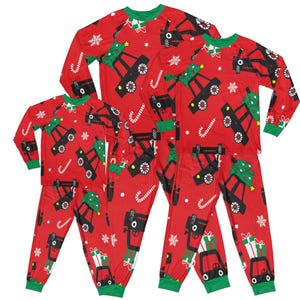 May include: Red Christmas pyjamas with a truck carrying a Christmas tree design. The pyjamas are available in three sizes.