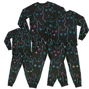 Pode incluir: Conjuntos de pijama pretos com um design repetido de rosto de gato em cores neon. As camisas e calças de manga comprida apresentam um padrão de rostos de gato delineados em azul, verde, rosa e roxo. Os pijamas são feitos de um material macio e confortável.