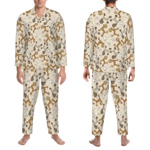 Puede incluir: Pijama beige con un patrón de caniches de dibujos animados marrones y blancos. El pijama tiene una camisa abotonada y pantalones largos.