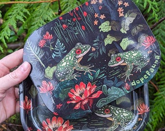 May include: A black metal rolling tray with a green and red floral design featuring frogs and the text "dopefauna".