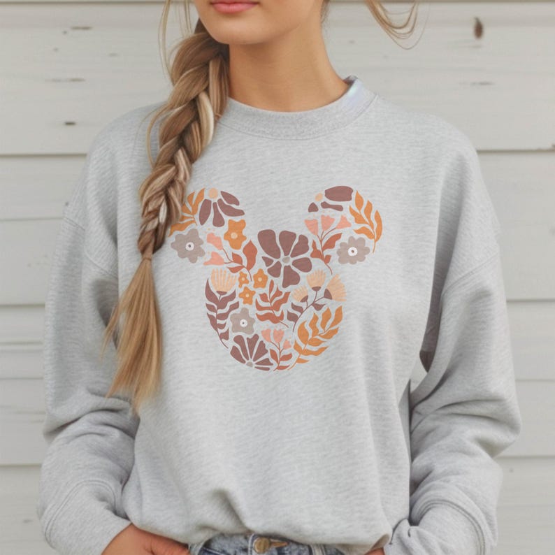 Pu&ograve; includere: Una felpa grigia con un design floreale di Topolino in tonalit&agrave; arancio, rosa e marrone.