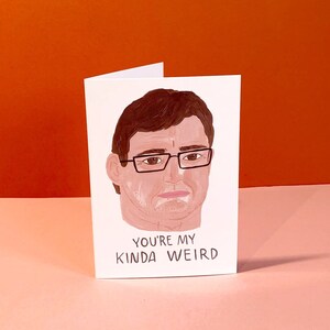 May include: A white card with a cartoon illustration of a person wearing glasses. The text on the card reads "You're my kinda weird."