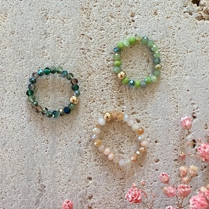 Peut inclure: Trois bagues en perles avec des accents dorés. Les bagues sont faites de perles vertes, beiges et vert clair.