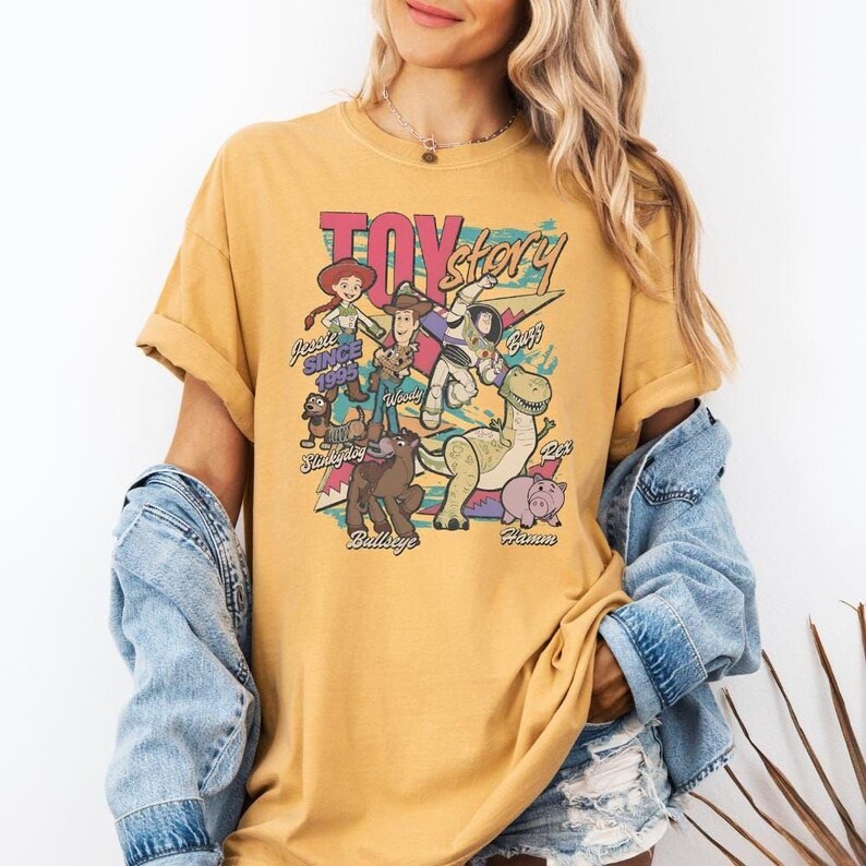 A woman wearing a yellow t-shirt with a graphic design featuring characters from the Toy Story movie.