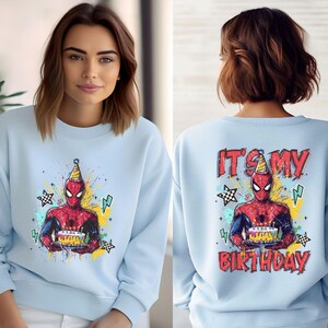 A woman wearing a light blue sweater with a Spider-Man graphic and the text "It's my birthday" printed on the back.
