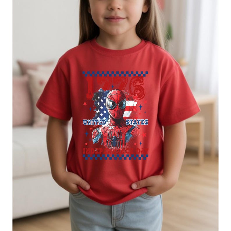 May include: Red t-shirt featuring a graphic of Spider-Man with a patriotic design. The design includes the text "1776", "United States", and "Independence Day" in blue and white. The shirt is short-sleeved.