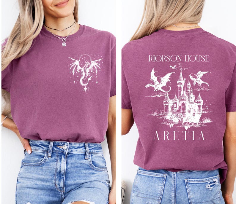 May include: A mauve t-shirt with a white dragon and star design on the front and a castle with dragons on the back. The text "RIORSON HOUSE ARETIA" is printed on the back of the shirt.