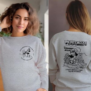 May include: A gray sweatshirt with a black and white illustration of Mickey Mouse on a steamboat. The text "Mickey Mouse Sound Cartoon" is above the image and "Steamboat Willie" is below the image. The text "A Walt Disney Comic by UB Iwerks" is at the bottom of the image.